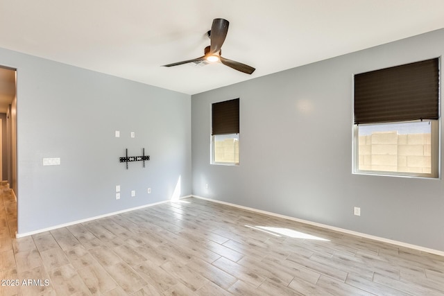 spare room featuring ceiling fan, light wood-type flooring, and baseboards