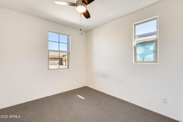 empty room with baseboards, dark colored carpet, a ceiling fan, and a healthy amount of sunlight