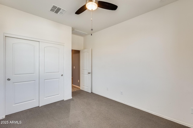 unfurnished bedroom with a closet, dark carpet, visible vents, and baseboards