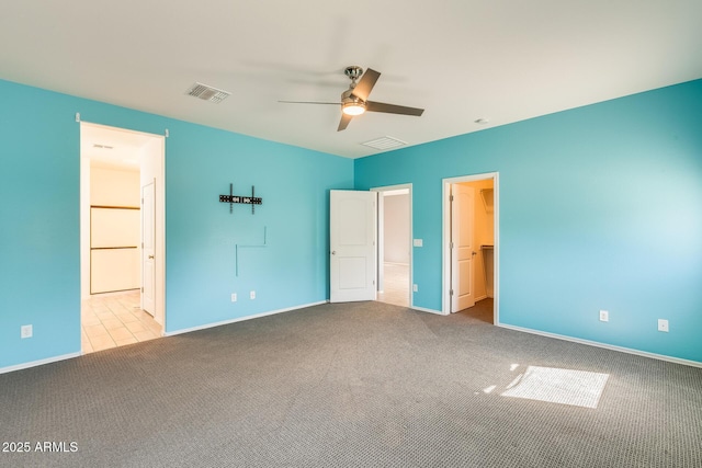 unfurnished bedroom featuring baseboards, carpet flooring, visible vents, and a walk in closet