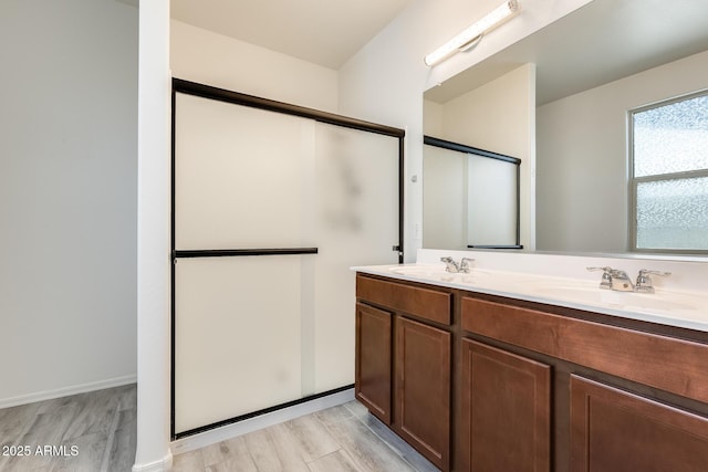 bathroom featuring double vanity, wood finished floors, and a sink