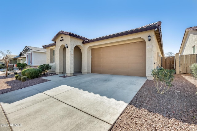 mediterranean / spanish-style house with an attached garage, fence, a tile roof, concrete driveway, and stucco siding