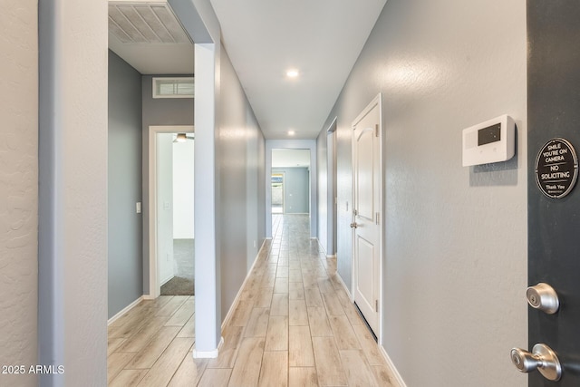 corridor featuring wood finish floors, visible vents, and baseboards