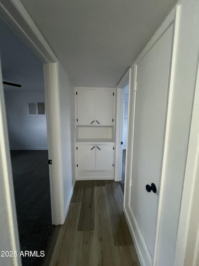 corridor featuring visible vents, dark wood finished floors, and baseboards