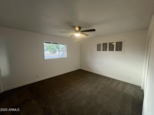 empty room with ceiling fan, baseboards, visible vents, and dark colored carpet