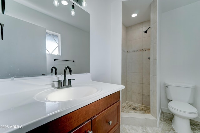 bathroom with toilet, a tile shower, and vanity