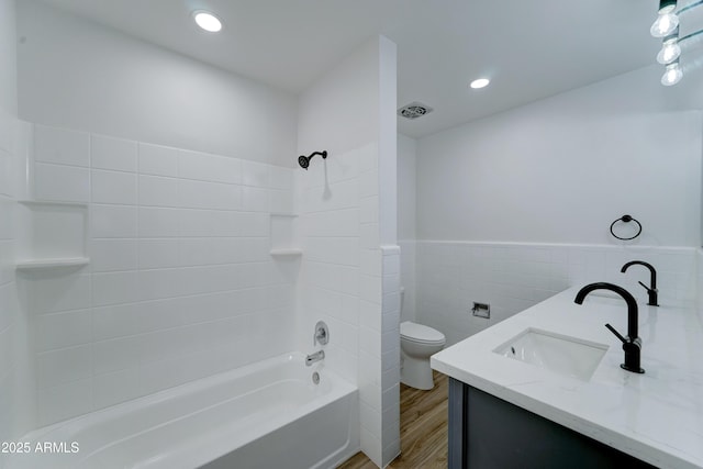 full bath featuring wainscoting, toilet, wood finished floors, tub / shower combination, and tile walls