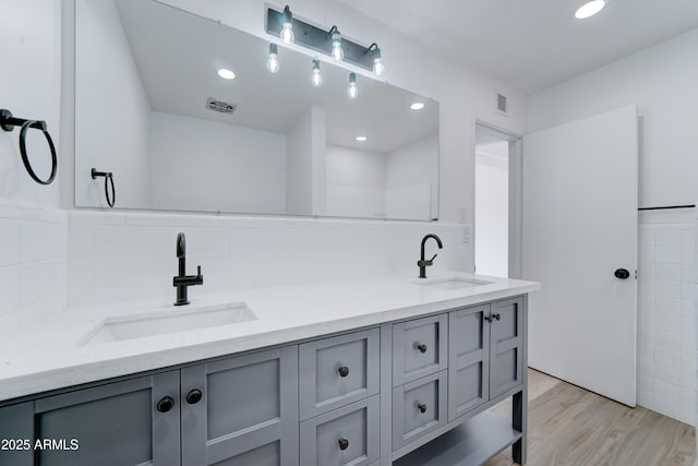 full bathroom with double vanity, wood finished floors, a sink, and visible vents