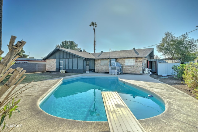 back of house featuring a fenced in pool, board and batten siding, a patio area, fence, and a shed