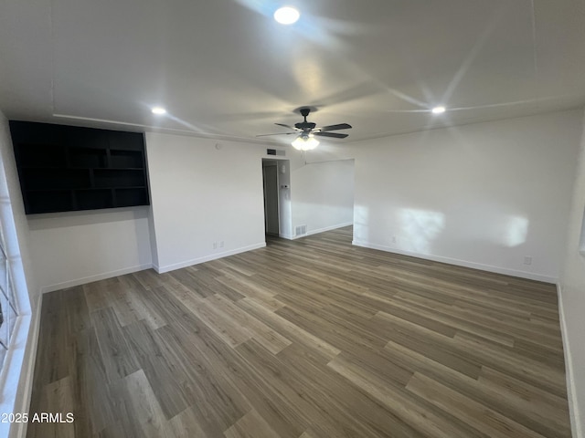 spare room with visible vents, ceiling fan, baseboards, and wood finished floors