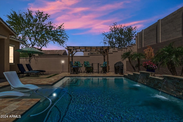 pool at dusk with pool water feature and a pergola