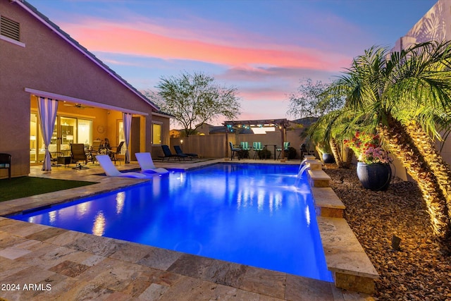 pool at dusk featuring a patio area and pool water feature