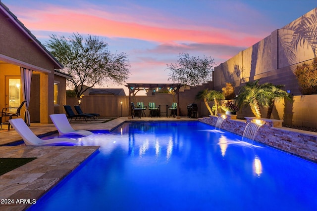 pool at dusk with a patio and pool water feature