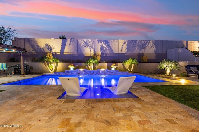 pool at dusk featuring a patio area and pool water feature