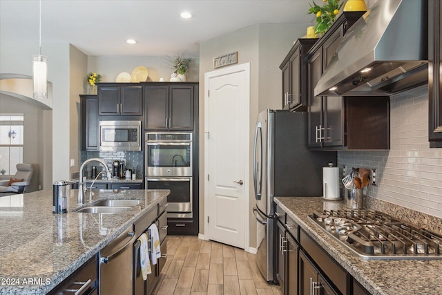 kitchen featuring backsplash, sink, stainless steel appliances, and wall chimney range hood