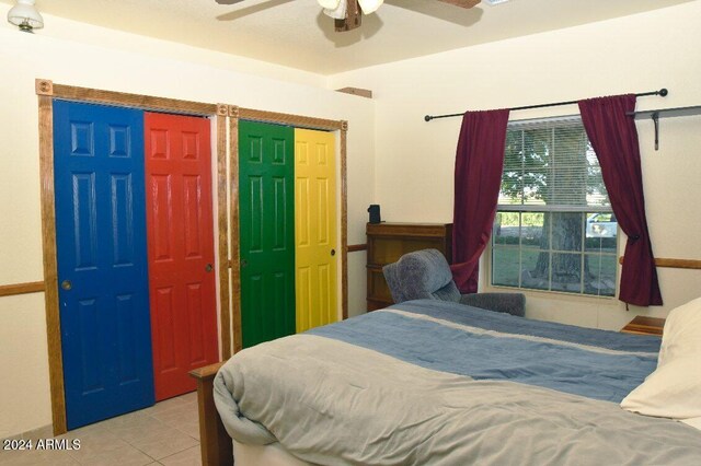 tiled bedroom featuring multiple closets and ceiling fan