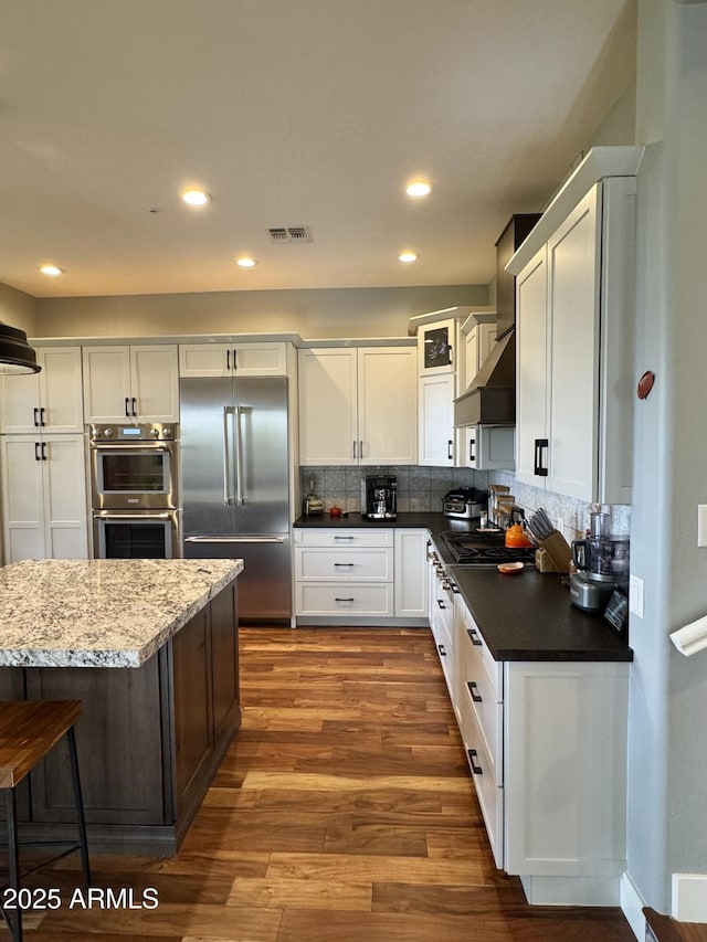 kitchen with decorative backsplash, white cabinetry, and appliances with stainless steel finishes