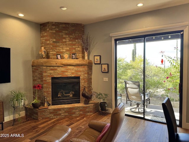 living room with hardwood / wood-style floors and a brick fireplace