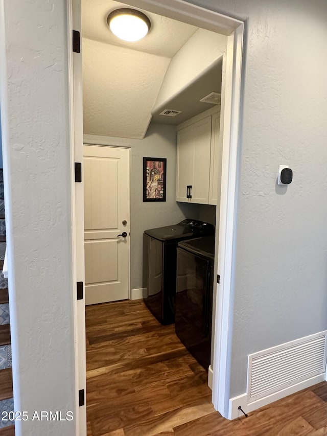 laundry area featuring cabinets, dark hardwood / wood-style floors, and washer and clothes dryer