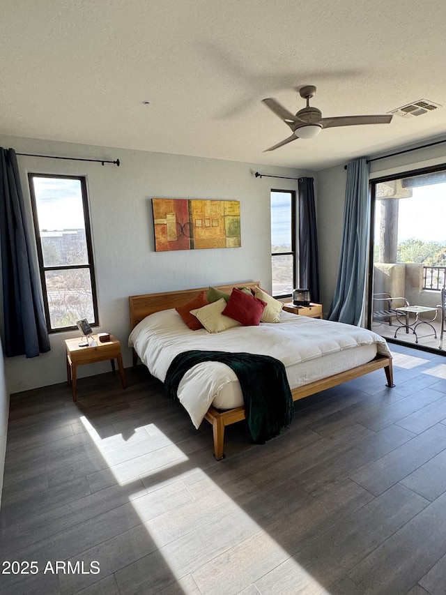 bedroom featuring multiple windows, wood-type flooring, a textured ceiling, and ceiling fan