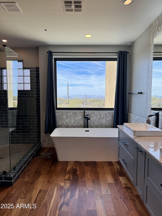 bathroom featuring a wealth of natural light, hardwood / wood-style floors, vanity, and tile walls