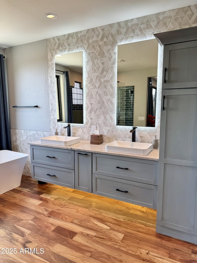 bathroom with hardwood / wood-style floors, vanity, a bathtub, and tile walls