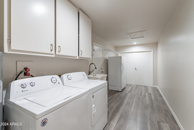 washroom with washing machine and clothes dryer, light hardwood / wood-style flooring, cabinets, and sink