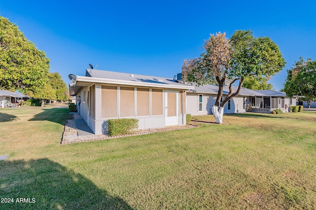 back of house featuring a lawn and a sunroom