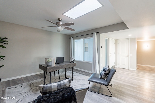 office area featuring a skylight, light hardwood / wood-style flooring, and ceiling fan