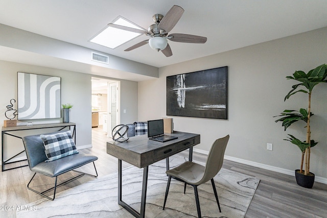 office featuring a skylight, ceiling fan, and hardwood / wood-style flooring