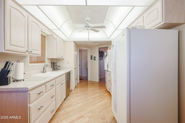 kitchen featuring light wood-type flooring, white refrigerator, a raised ceiling, dishwasher, and ceiling fan