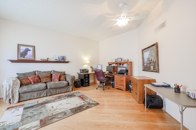 office with ceiling fan, vaulted ceiling, a textured ceiling, and light hardwood / wood-style flooring