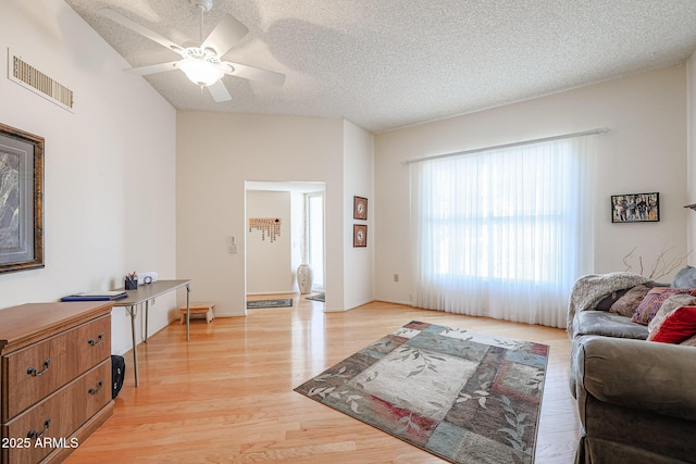 living room featuring ceiling fan, a textured ceiling, and light hardwood / wood-style floors