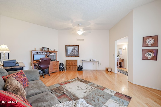 living room with hardwood / wood-style flooring, ceiling fan, and a textured ceiling