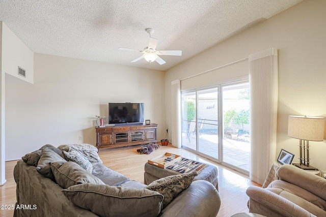 living room with ceiling fan, lofted ceiling, light hardwood / wood-style flooring, and a textured ceiling