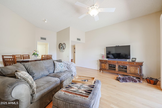 living room featuring lofted ceiling, hardwood / wood-style floors, a textured ceiling, and ceiling fan