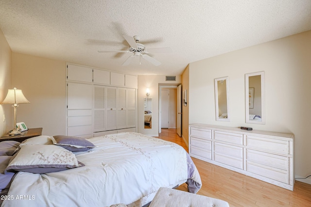 bedroom featuring ceiling fan, light hardwood / wood-style floors, a closet, and a textured ceiling