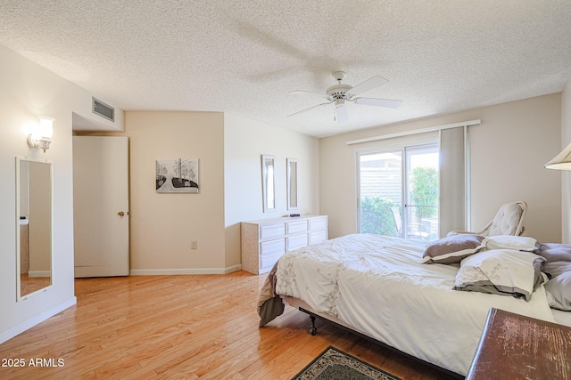 bedroom with ceiling fan, a textured ceiling, and light hardwood / wood-style floors