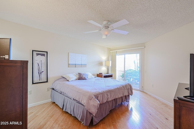 bedroom with ceiling fan, access to outside, a textured ceiling, and light hardwood / wood-style floors