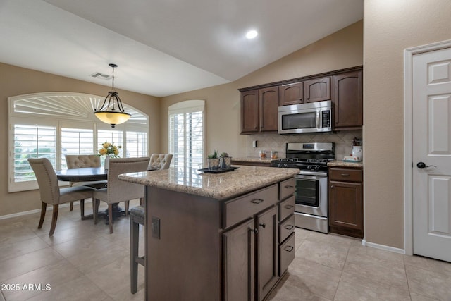 kitchen featuring visible vents, pendant lighting, a kitchen island, backsplash, and stainless steel appliances