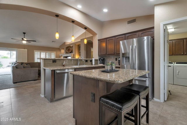 kitchen with visible vents, a sink, arched walkways, appliances with stainless steel finishes, and lofted ceiling