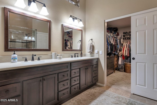 full bathroom with double vanity, a shower with door, a walk in closet, and a sink