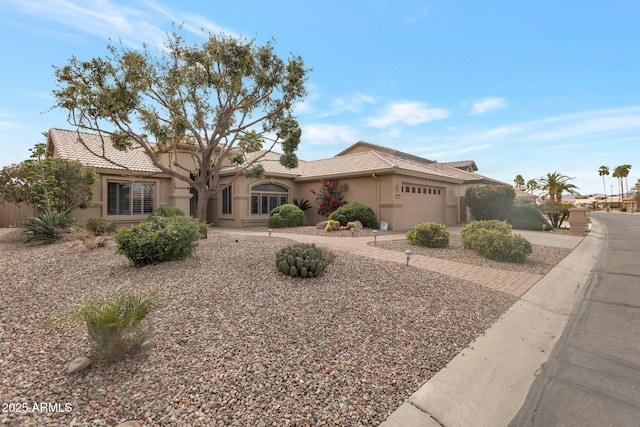 view of front of property with a tile roof, a garage, driveway, and stucco siding