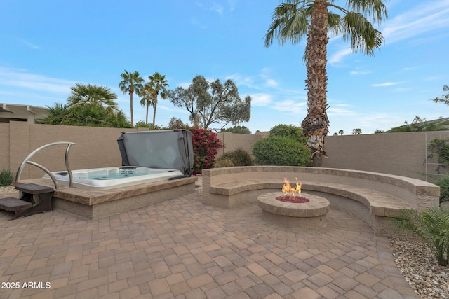 view of patio / terrace featuring a covered hot tub, a fire pit, and fence