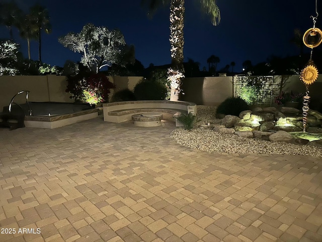 patio at night featuring fence and an outdoor fire pit