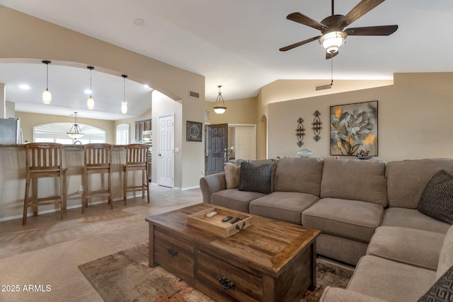 living room with visible vents, arched walkways, ceiling fan, and vaulted ceiling