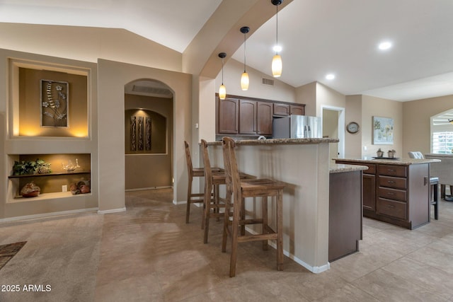 kitchen with built in shelves, arched walkways, a peninsula, stainless steel fridge with ice dispenser, and vaulted ceiling