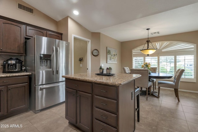 kitchen with visible vents, lofted ceiling, pendant lighting, and stainless steel refrigerator with ice dispenser