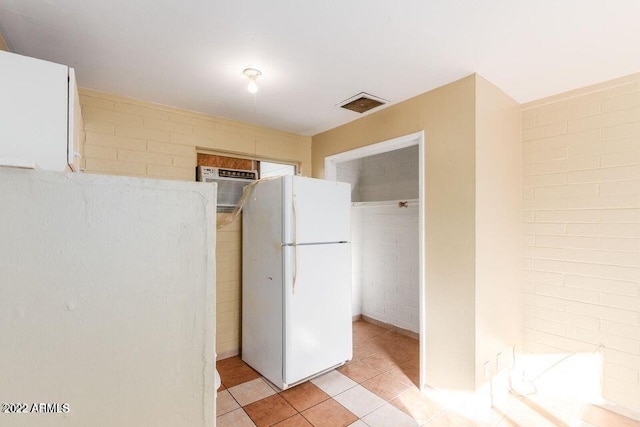 kitchen featuring visible vents, light tile patterned floors, a wall mounted AC, and freestanding refrigerator