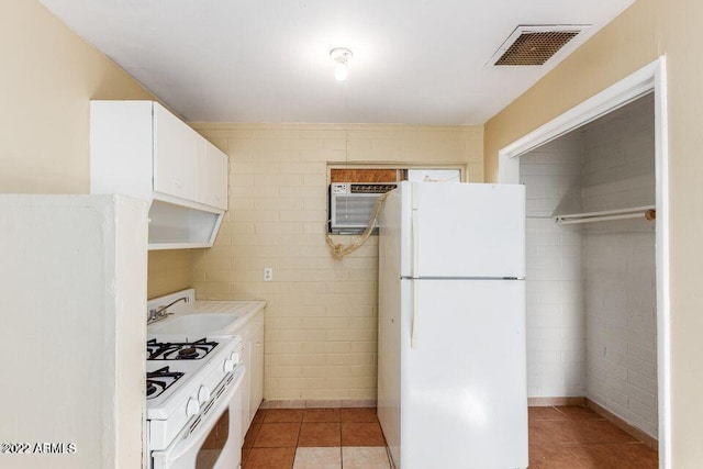 kitchen with light tile patterned floors, white appliances, a sink, visible vents, and a wall mounted air conditioner